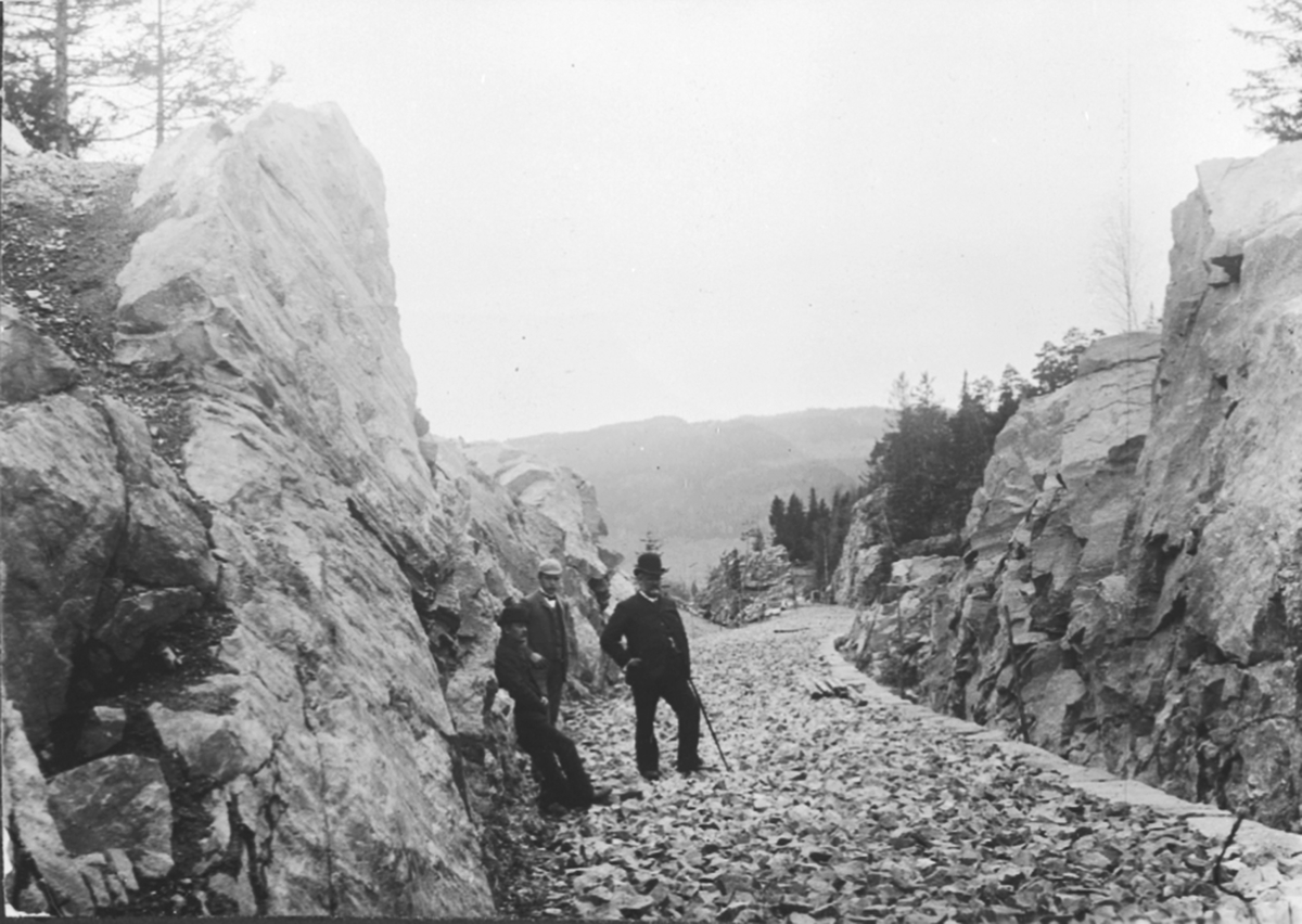 Jernbaneutbygging, anleggsarbeid, fra skjæringen sprengt gjennom fjellet til jernbanespor, sprengt gjennom fjellet, før jernbaneskinner ble lagt, ved Rise gård, Ring, Ringsaker.