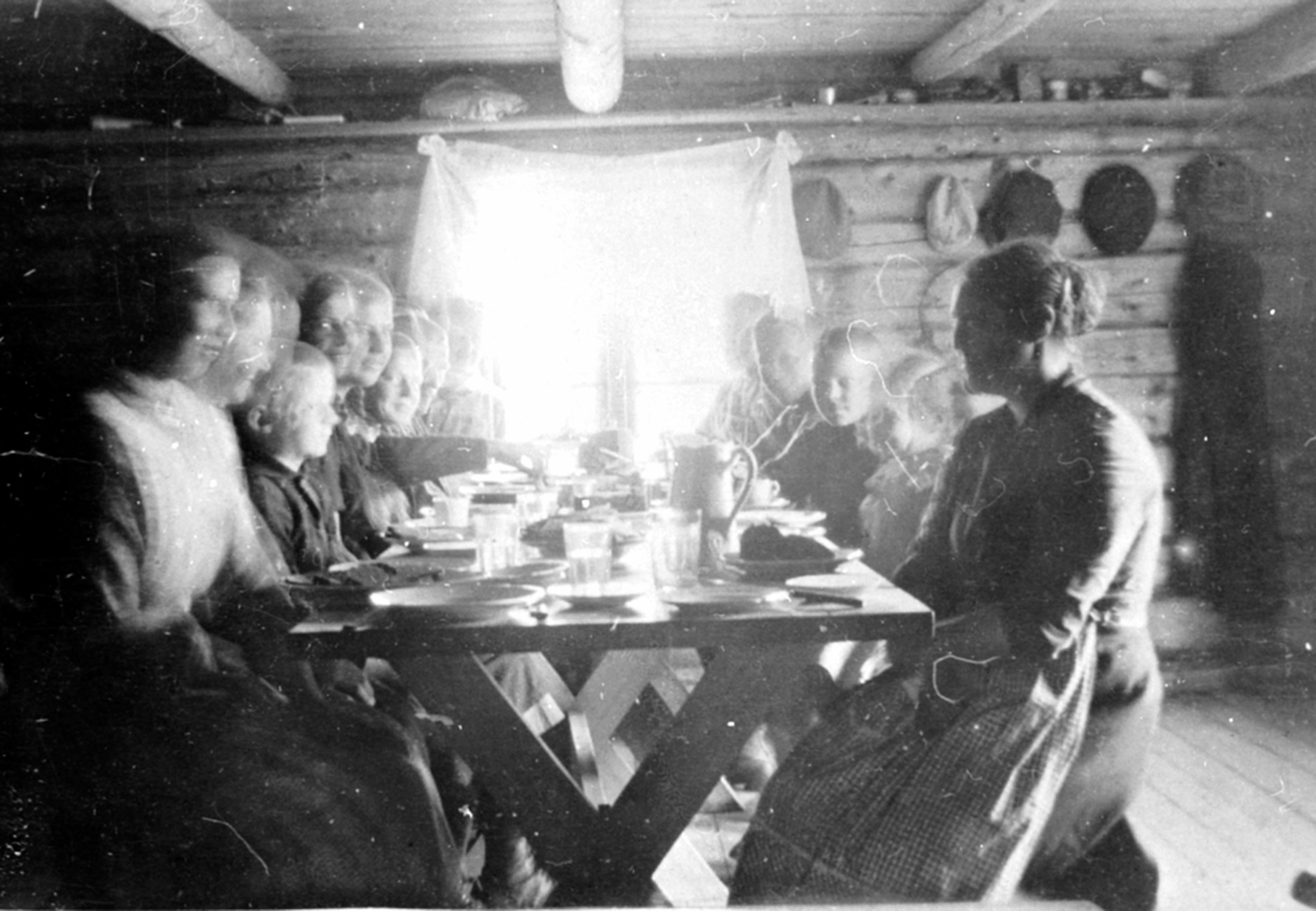 Interiør, størhuset på Øyungen seter, Ringsaker fjellt. Familien Løken fra Granerud gård, Brumunddal samlet til måltid ved bordet.