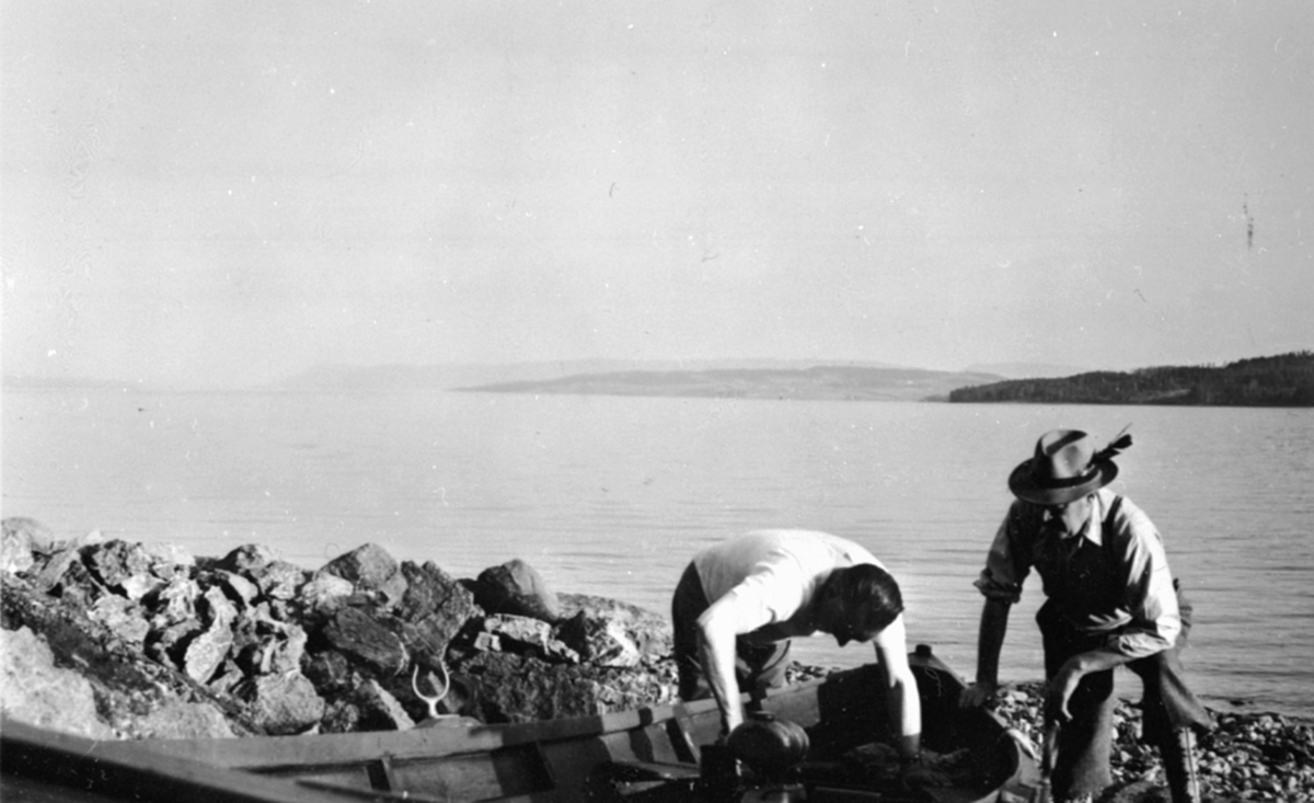 To menn ved motorbåt i strandkanten på Jessnes, Ringsaker.