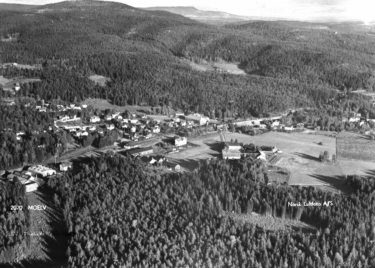 Flyfoto av Moelv med omegn, Mo gård, Moelv stasjon, Moelv sentrum, Moskogen,