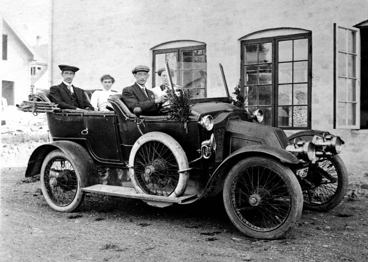 Bil, Renault ca. 1911-1912 modell. registreringsnummer E-39. Passasjerer er fotograf Simen Baardseth, Dagny Baardseth født Ovesdatter, sjåfør Even Baardseth ? og Mathea Baardseth ?.

---- kommentar start ----
Det kan ikke være Even som kjører. I følge folketellingen av 1910 var han født i 1903! Det kan være en annen Baardset, da mine opplysninger kommer fra Baardset nedre, g. nr. 264, B. nr. 1. 

Noen flere kommentarer.  Baardseth nedre stemmer. Men Simen var bror av gårdeieren Mathias.  Mathias var født i 1866, Simen i 1877.  Simen titulerer seg fotograf. Simen bodde i sidebygningen.  Mathea Langaard var tjenestepike på gården i 1910.  Kanskje hun giftet seg med Simen, han står som ugift. 
Men bilens eier kjenner vi ikke. Da skulle mye være på plass! Lykke til videre. 
---- kommentar slutt ----
