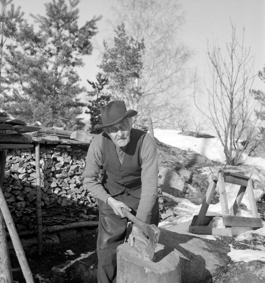 Portrett mann. Anton Enemo. Stående ute foran vedstabler, kløver ved med øks.  Vinter. 