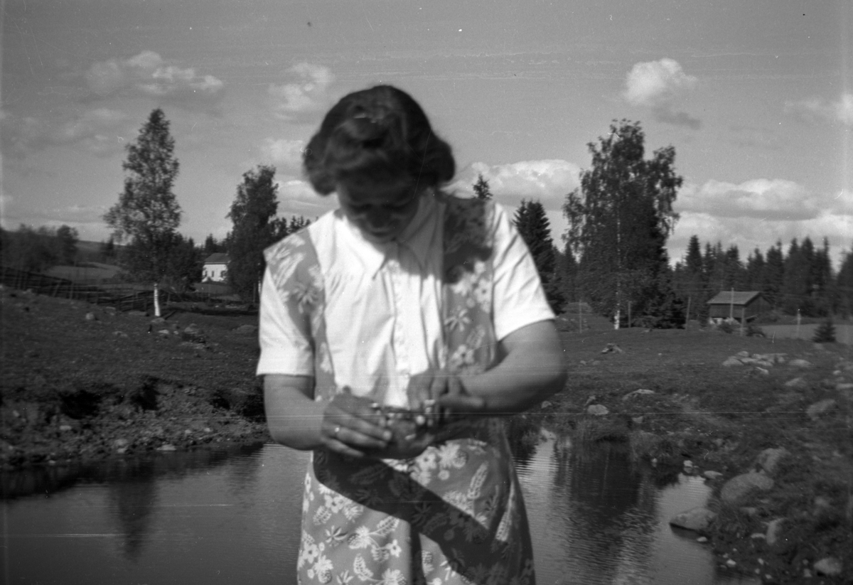Karen Tomter ved Smiudammen i kulturbeitet Finborudroa på Søndre Tomter (Ner-Tomter) ca 1950. Til venstre i bakgrunnen naboeiendommen Olstad og låven fra husmannsplassen Grindstua. Husmannsplassen var i drift til ca 1910. 