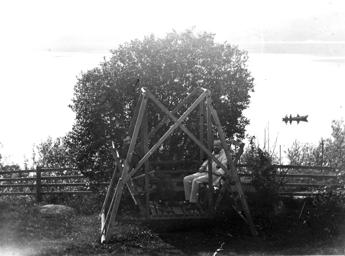 To menn i huskestativ, hagegjynge. Baneminde pensjonat, Espa. Mons Hestnæs kom hjem fra Amerika ca. 1900 og hadde med seg tegninger på husker og det ble laget en del slike. Mons Hestnæs som sitter til venstre. 