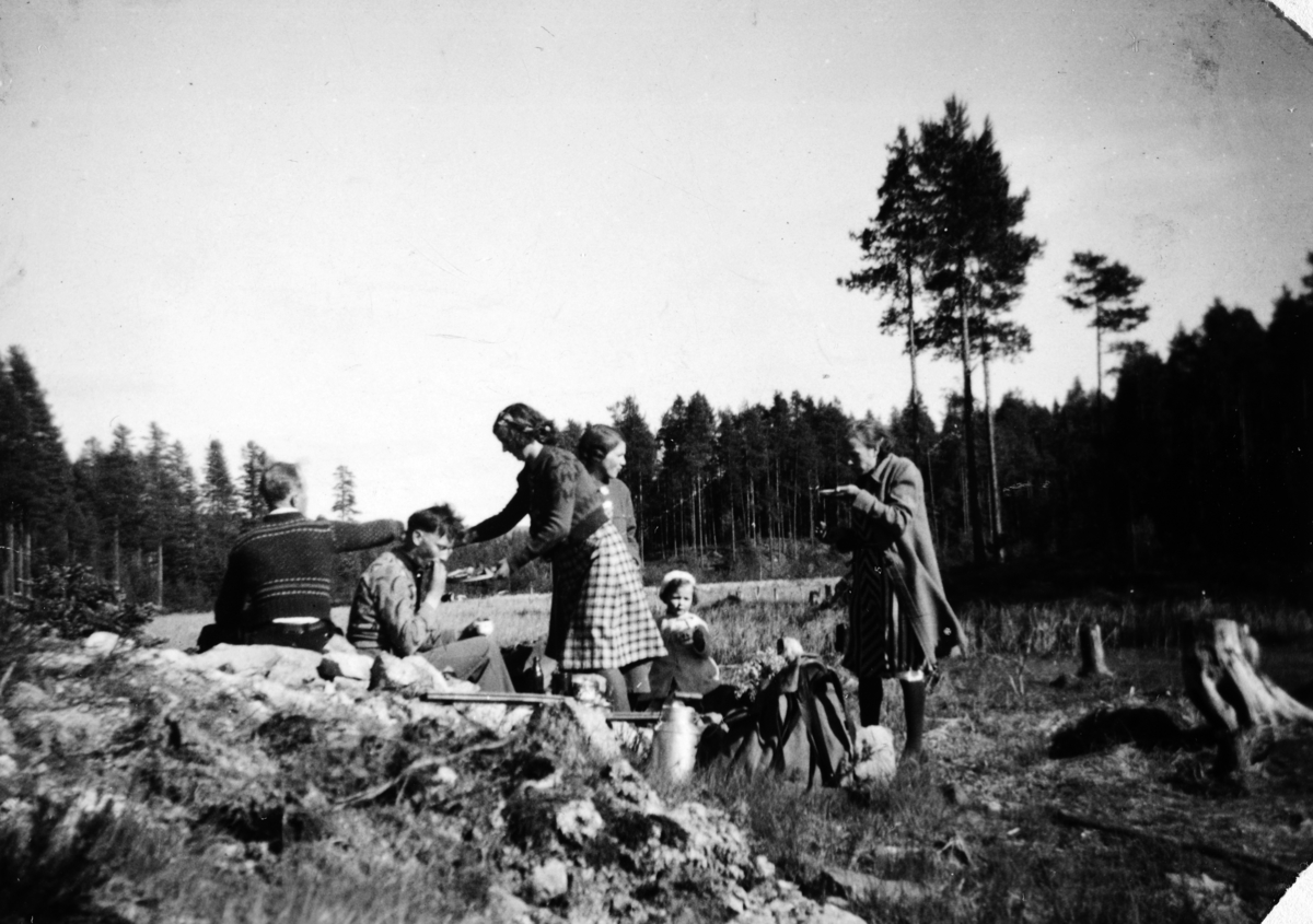 Bærtur, bærplukking i Romedal almenning ca. 1940. Matpause. Solveig Stenhaug (lita jente), hennes foreldre, ukjente. . 