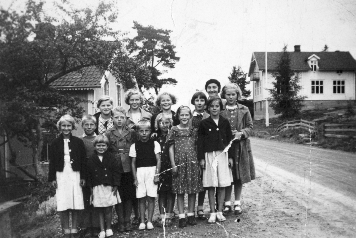 Gruppe, 14. Søndagsskolen på Minnesund på utflukt til Tangen i 1936 eller 1937. Ulvin skole i bakgrunnen? De ble kjørt på lastebil. Søndagsskolelærerinnen står bak t. h, og til venstre for henne står Ruth Evenstad fra Stange, f. 1925, gift Ødegaard. Hun var på besøk hos sin søster Ella, da mannen Hjalmar Dahl var telegrafist på Minnesund. Til venstre for Ruth står Marit Doknes. Gerd Frenning nest til venstre foran (hvitt skjørt) og sannsynligvis Arvid Frenning til høyre for Gerd.