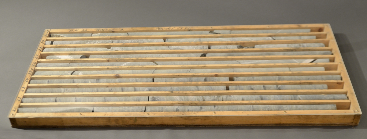 Rektangulær, nummerert, ganske flat kasse med systematisk organiserte nummererte rom for bergprøver. Kassen inneholder ti avlange rom, og i hvert ligger bergprøver.