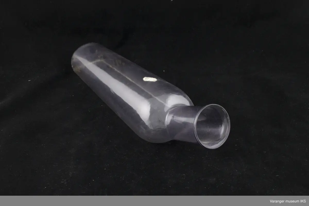Urinflaske for sengeliggende i plast. Målestokk på flaskens underside.