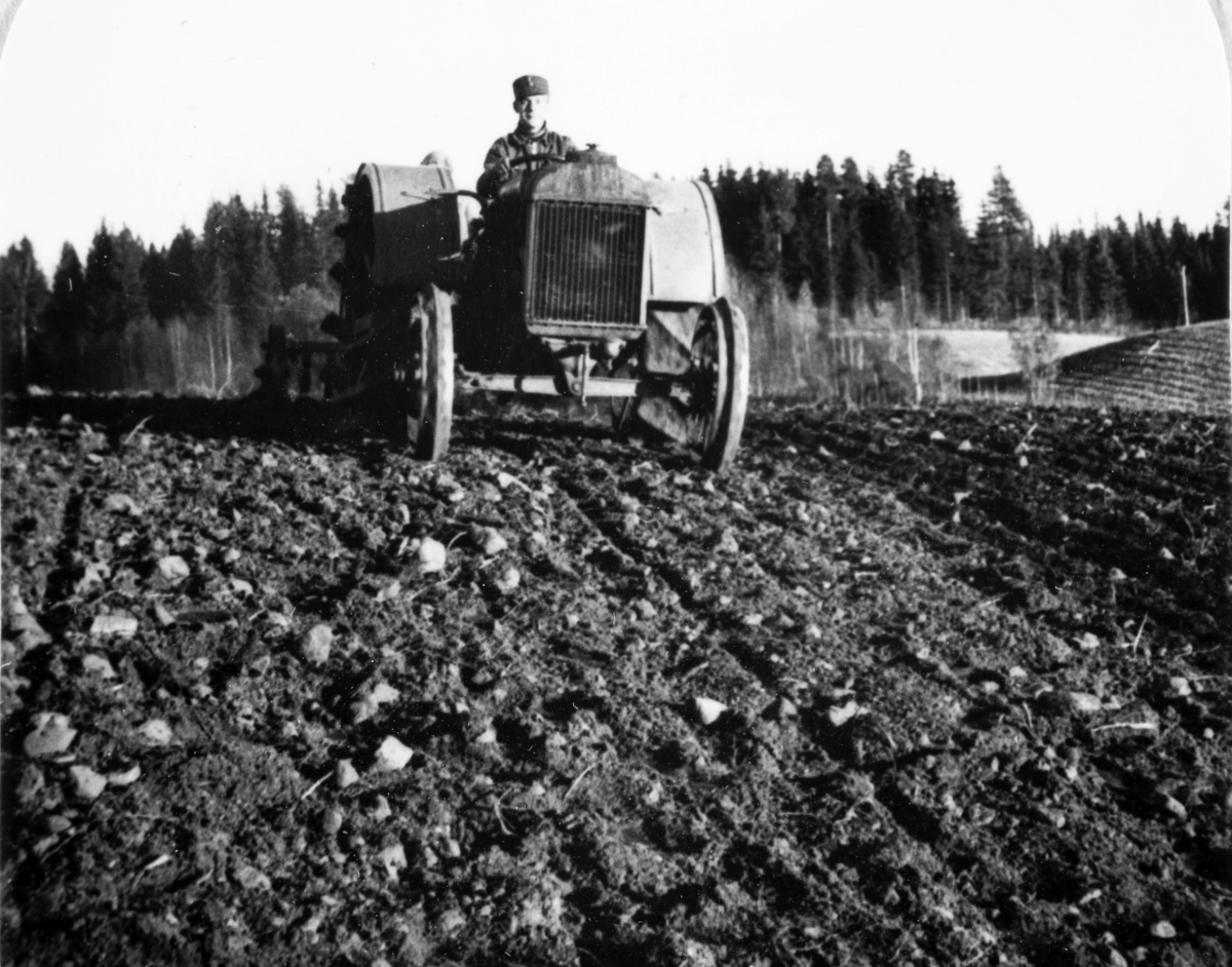 Lagfører Irgens kjører traktor på Lund gård. AT-tjeneste på Ådalsbruk i Løten, 26. august 1942 til 26. november 1942. Arbeidsdistrikt nr. 1. Arbeidsfylking IV. Sveit nr. 5. Forleggingssted Ådalsbruk. Arbeidstjenesten under 2. verdenskrig.