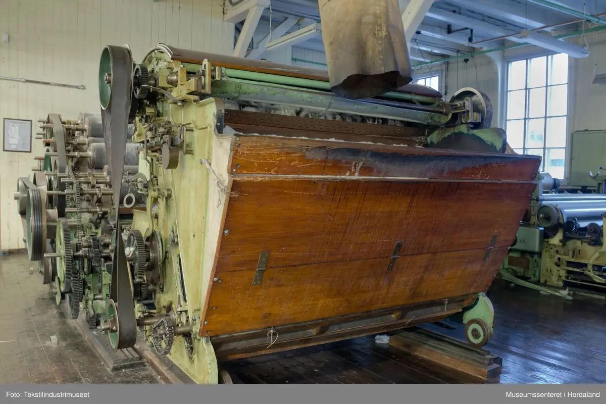 Kardeverk med tre kardemaskiner som er kopla saman og arbeider i serie, frå Oscar Schimmel & Co i Chemnitz, Tyskland. Frå ullinntaket i eine enden av maskina, blir ulla ført over valsar med metallkardar på, som fjernar ureinheiter og løyser opp floker i ullfibra. Ulla blir karda ein gong før den går over eit transportband i tre, blir snudd og karda to gonger til før det karda ullfloret går gjennom ein flordelar som deler det opp i remser. Remsene blir rulla opp på store metallspolar, og blir då kalla forgarn. I forgarnet ligg alle ullfibra etter kvarandre, men garnet er utan styrke og må spinnast for å bli til brukbart garn. 

Maskina var i bruk på Salhus Tricotagefabrik (1859-1989), og hadde her internt maskinnummer 5. Kardeverket står i hesteskoform med ullinntaket og ei kardemaskin på ei sida, to kardemaskiner og flordelaren på andre sida, og eit transportband i tre som bindeledd mellom dei to. Kardeverket blir drive av tre elektriske motorar som er festa til golvet på innsida av 'hesteskoen'. Maskina er grønmåla, med mange dekorative tannhjul med bua eiker, typisk for maskiner frå rundt 1900.

Det har seinare blitt montert ein støvsugar på kardeverket, som syg opp støv ved flordelaren, og transporterer det tilbake til ullinntaket. Røyra til støvsugaren ser 'heimelaga' ut, og er sett saman med bl.a. teip og ulike typar røyr.