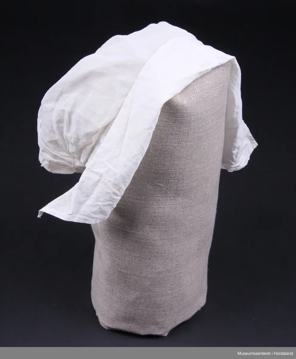 Svært tynt bomullslerret og brem i litt tjukkare lerret ( men framleis tynt - batist).
Strikk bak i nakken. Sølve hua er i eit stykke, medan bremmen har saum midt oppe på hovudet.Smal maskinsydd fall på bremmen.