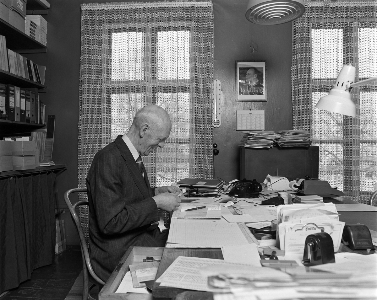 Emil Lies bokhandel i Strandgata 63, Hamar,  interiør. Bokhandler Alfred Wangen ved kontorpulten. Kontorarbeid. Forretningen ble nedlagt i 1982.. 