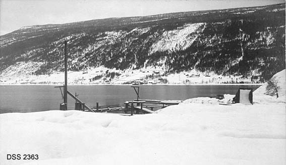 Fra A/S Rjukanfos' sandtak på Mårvikmogen i Tinn.  Bryggeanlegget i forgrunnen.  På motsatt side av sjøen ser en ei liside med innmarka på garden Sigurdsrud ned mot sjøen og skog ovenfor.  Bebyggelsen på gardene er plassert på den øvre delen av de oppdyrkete arealene.  Vinteropptak med snødekte flater.