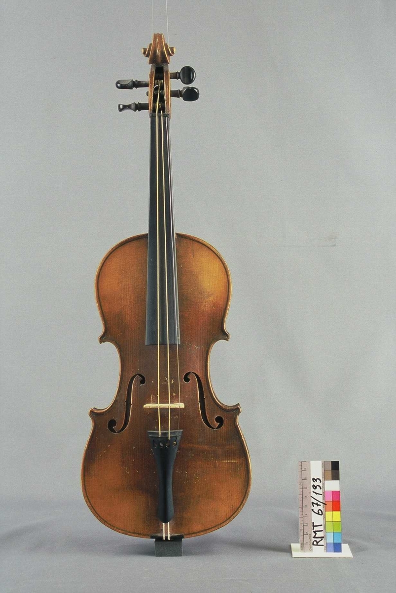 Strengeinstrument i mindre størrelse, 1/4 format(?). Lokk av gran, bunn og sarg ahorn. Lys lakkert. Gripebrett, strengeholder og endeknapp ibenholt. Sortmalte skruer. Mangler hjørneklosser.