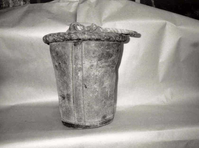 Bøtte av lær hvor det på oversida er sauma på ører hvor et hampetau er festa som hank, mangler bunn