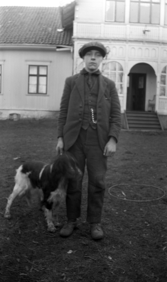 Ukjent gutt med en hund foran et hus. 