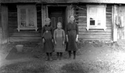 Tre ukjente jenter foran et hus.