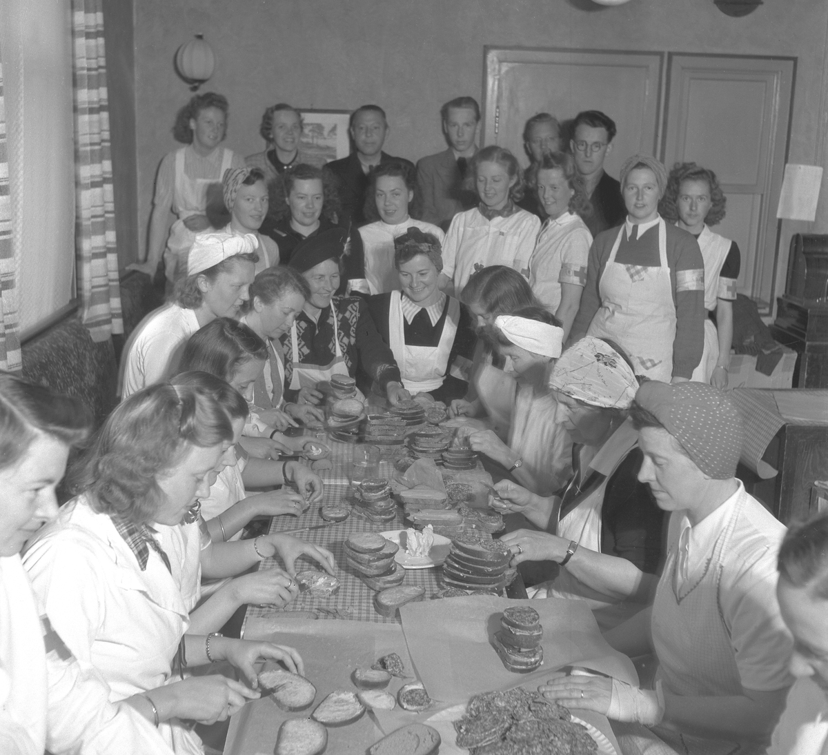 Hamar, fredsdagene i mai 1945, Torggata 21, leilgheten til fru Signe Klumsten, norske kvinner smører matpakker på dugnad til hjemmestyrken og de russiske fangene på Martodden,  
Se foto 2 for nummerert siluett: 5. Else Olausen (Haugaasen), 6. Hildegard Røhne, 7. Signe Klumsten, 8. Tulla Gundersen (g. Jahren), 12. Frisør Eric G. Lindmark, 13. Odny Sponberg, 14. Edel Raaen (f. Rosenlund), 15. Odd Granrud, 19. Gerd Kjendli (f. Haugaasen), 20. Olaug Hansen, 21. Borghild Bekkevold, 25. Gerda Lindmark.