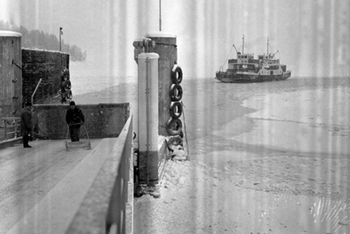 Påkjøringsrampen ved Mengshoel fergested. Mjøsfærgen legger til. Vinter. Rydding av snø på påkjøringsrampe.