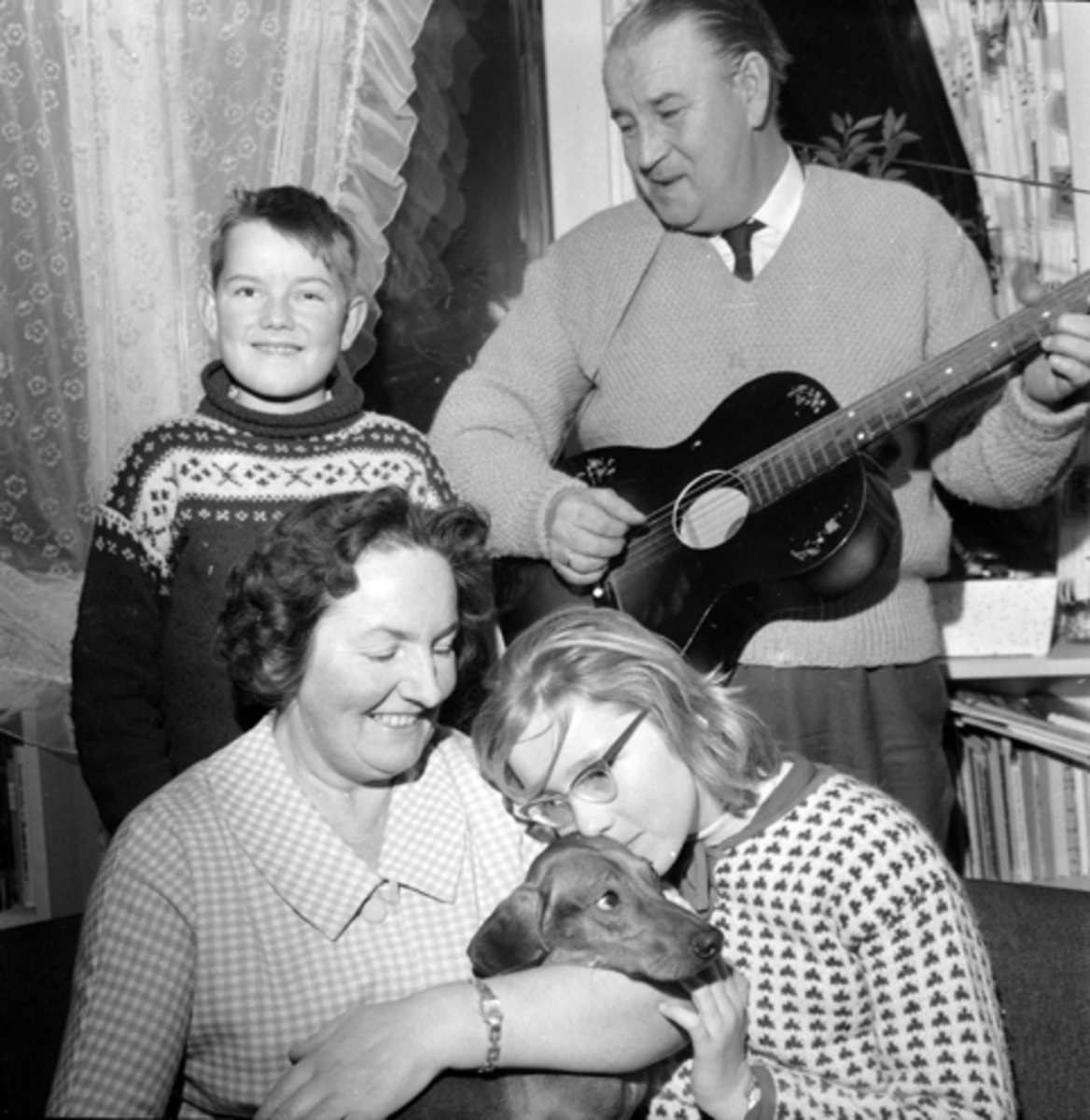 Nittedal, Familien Alf Prøysen spiller gitar, fra venstre Ketil (1851-) og foran Else Prøysen og Elin (1949-) med hund,