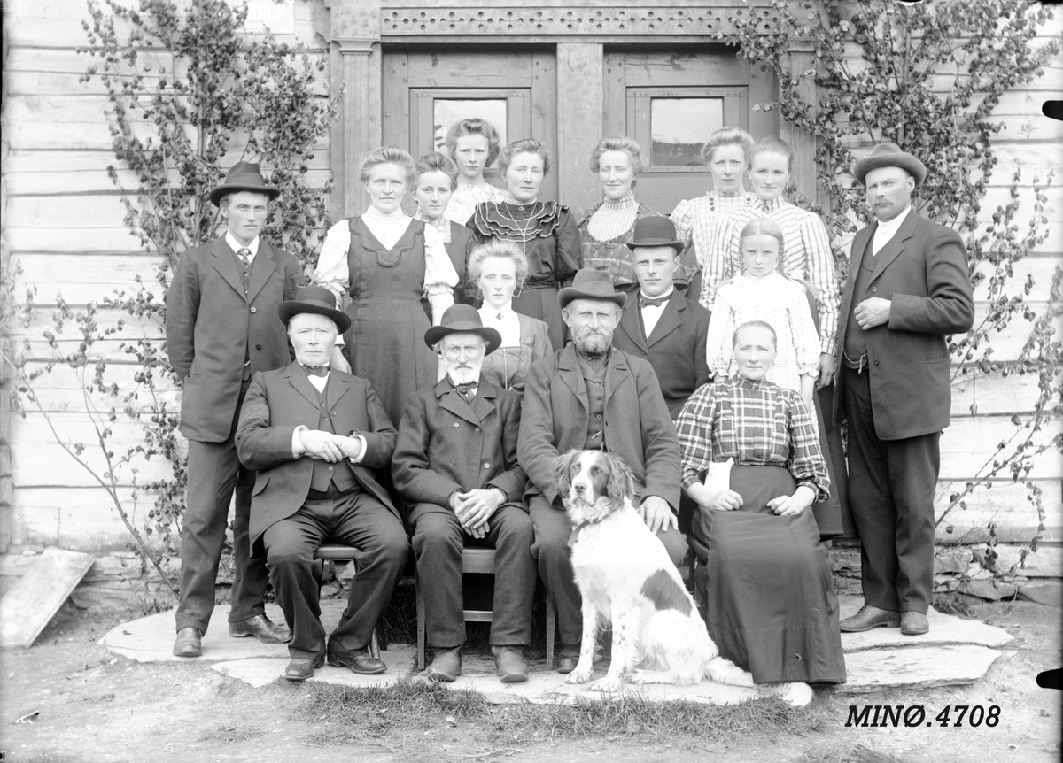Sannsynligvis en storfamilie foran hus, hund. 