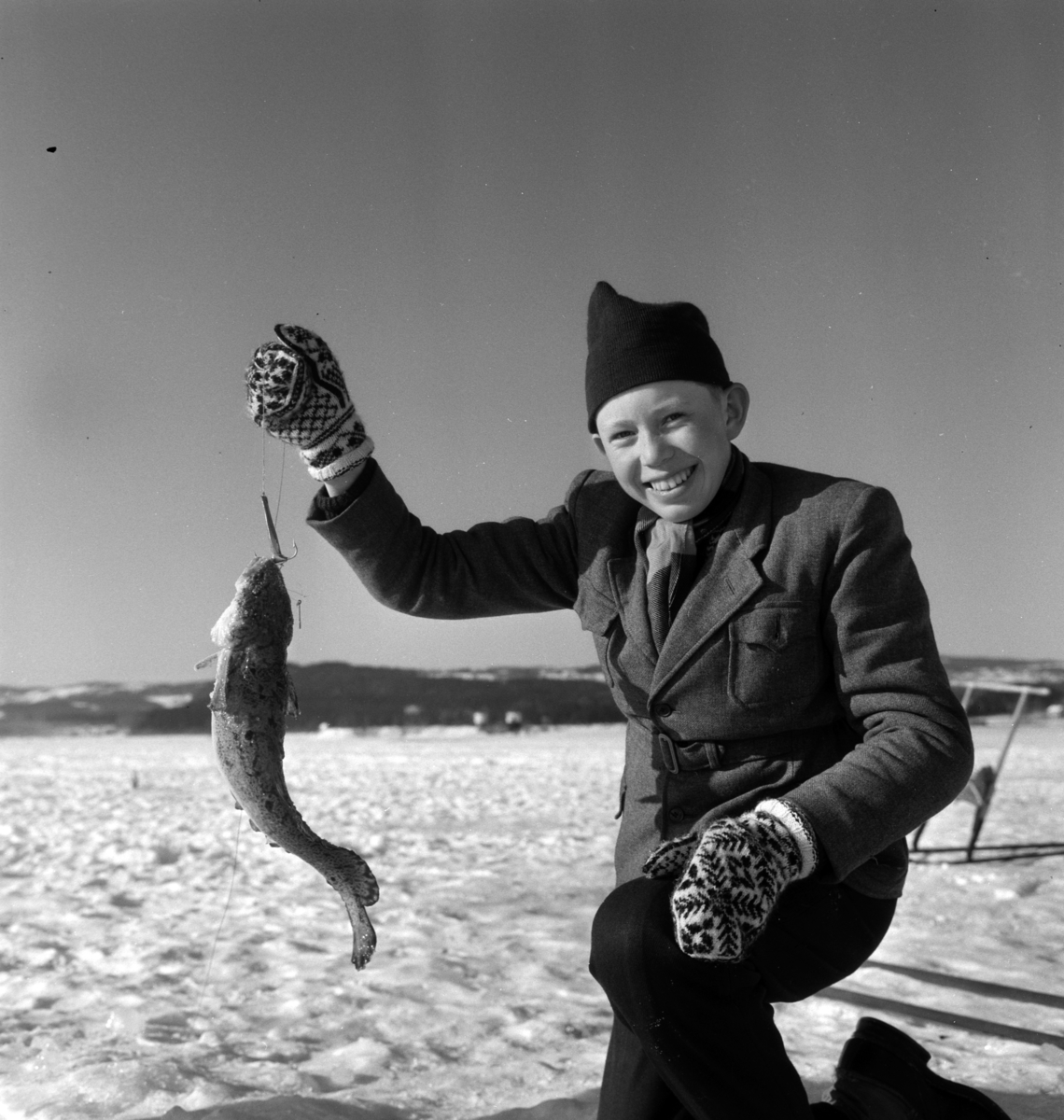 Pilkekonkurranse utenfor Strandsaga i Brumunddal 09. 03. 1958. Fiskekonkurranse på Mjøsisen. Isfiske. ukjent pilker. 
Premier i pilkekonkurransen var bla. en bil, Skoda 1958 modell, motorsykkel, kjøleskap, reiseradio. Se. Na-00293-31 og Na-00293-32 for flere opplysninger. 