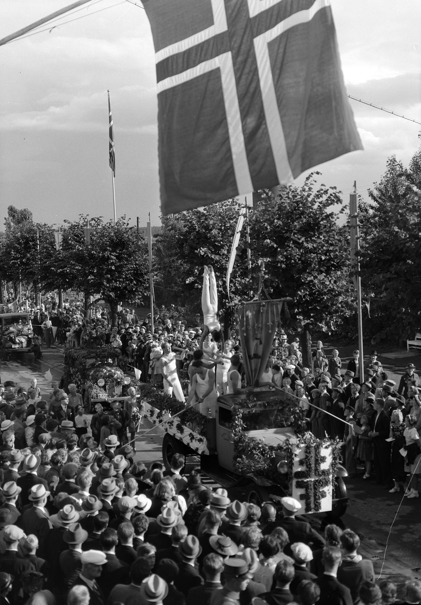 Hamardagen 1939, opptog i Strandgata, Lastebilkortesjen fra Utstillingsplassen til Stortorget, dagen var en todagers fest som samlet 50 000 mennesker, bilkortesje som representerte distriktets handel, håndverk og industri, publikum på fortauet,