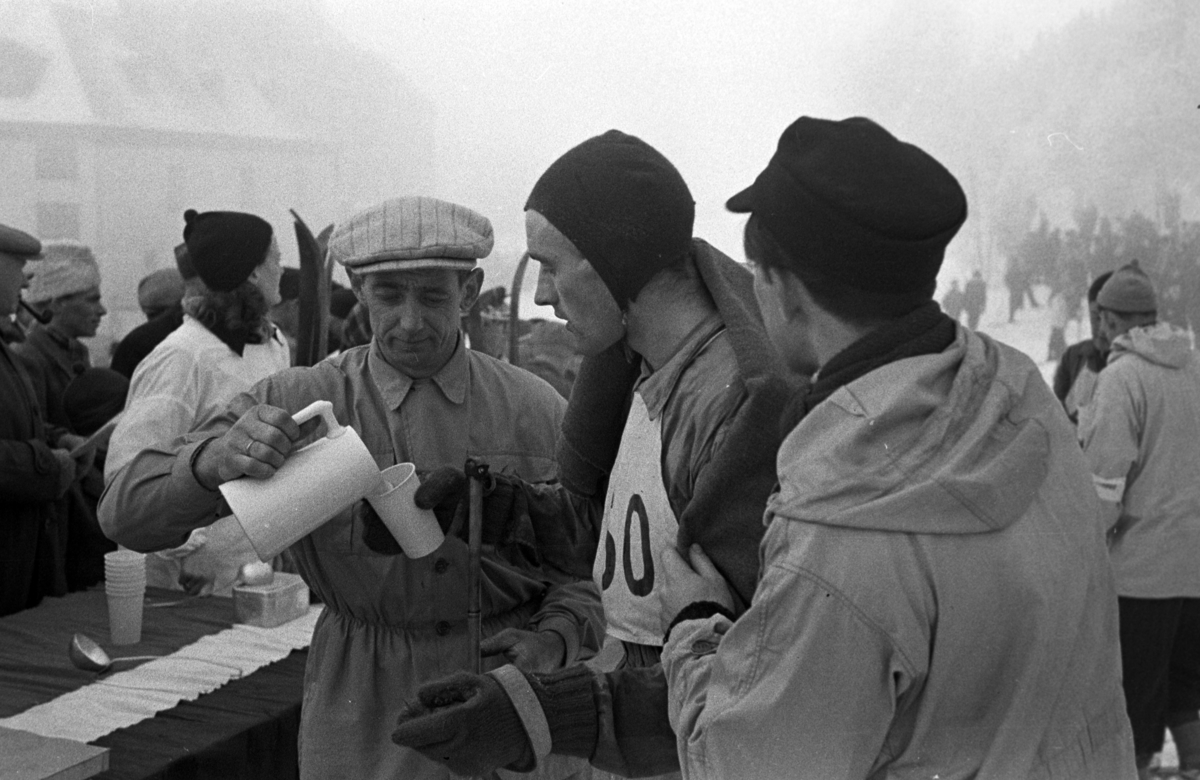 NM. Norgesmesterskap på ski, langrenn på Høsbjør i Furnes 1949. Skisport. Vinteridrett. Ukjent langrennsløper får drikke etter målpassering, 