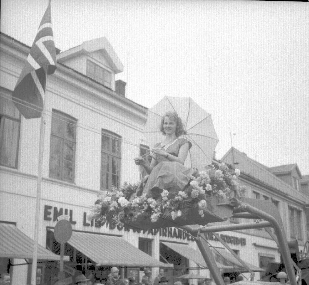 Hamardagen 1956, opptog, Strandgata , Ingrid Johansen, sittende i traktirskuffen. Hun er her 22 år gammel, og kontordame på Ham-Jern. Og var i 1956 årets "Ham-Jernpiken" 
blomster,traktor, lasteapparat.
