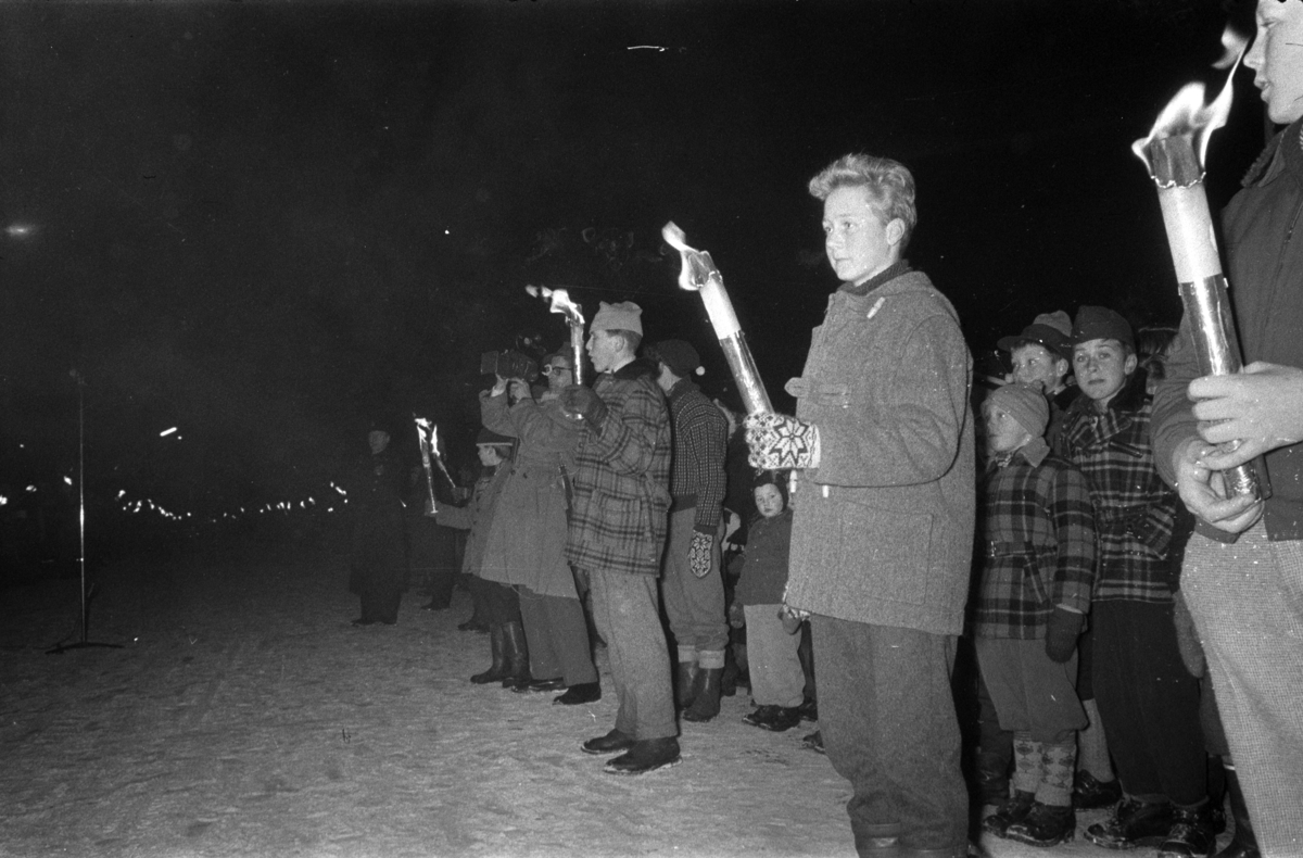 Egil Danielsen kommer hjem til Hamar etter å ha vunnet Olympisk gullmedalje i Spyd i Melbourne 1956. Folk langs Strandgata med fakler. 