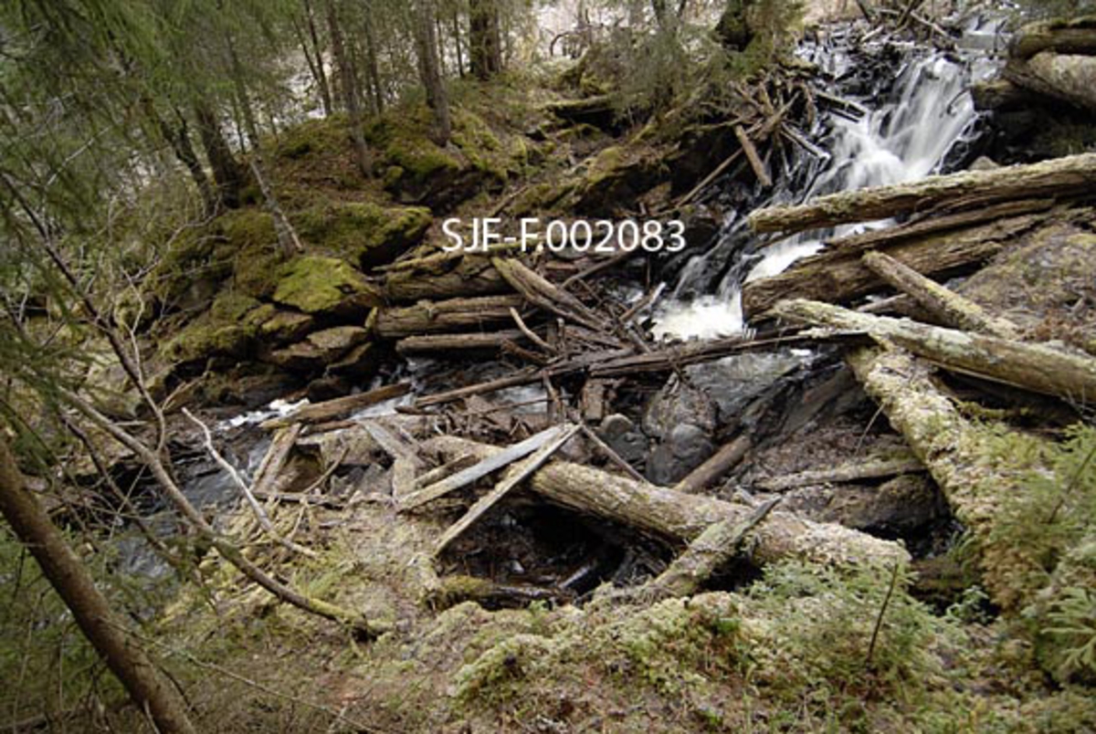 Fra Sagfallet i det lille vassdraget Anda (uttales Ana) på Storsjøens østside i Ytre Rendalen.  Her renner elva bratt nedover gjennom et berglandskap før den 70-80 meter lavere når den nedenforliggende innsjøen like sør for bruket Andråstøa.  Fotografiet er tatt fra den sørvestre sida av vassdraget, mot det stedet der oppgangssaga til Andrå-gardene lå.  Denne sterkt forfallne saga ble høsten 1963 demontert og flyttet til det daværende Norsk Skogbruksmuseum i Elverum.  Bildet viser fallet og en del mosegrodde stokker som allerede i 1963 var så dårlige at de ikke ble tatt med til museet.