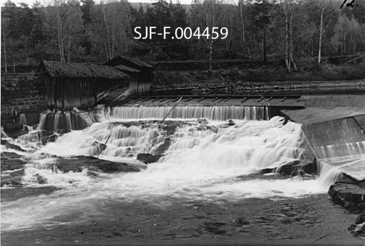 Vestre del av Geithusfossen, slik den så ut ved lav vannføring før Union-konsernet startet utbygging av fossen.  På dette fotografiet, som antakelig er fra 1958, ser vi at det er bygd en lav terskeldam.  Til venstre i bildet lå ei rekke med falleferdige trehus mot fossen. 