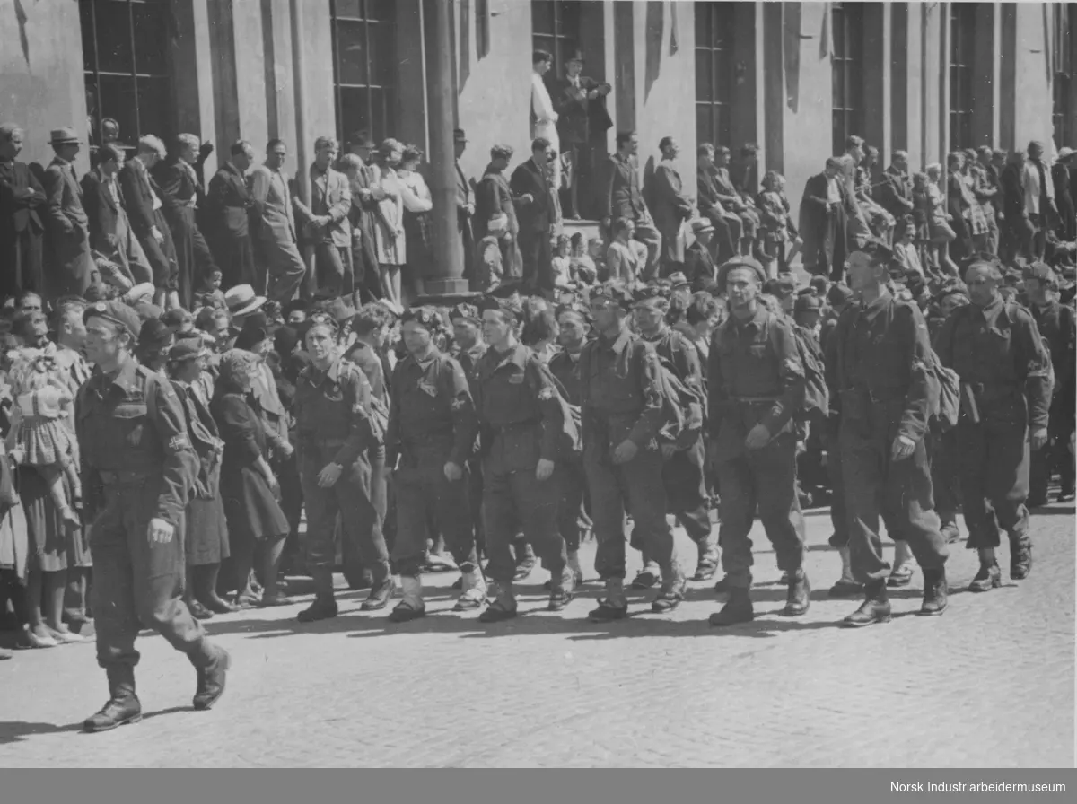 Til Oslo - parade for Kongen. Ledelsen i hjemmestyrkene (HS) A.16.2 marsjerer uniformerte i parade på Karl Johan. Publikum står langs gatene.