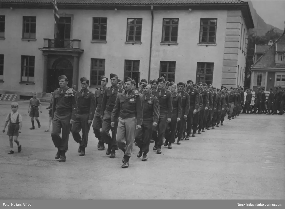 Amerikanske tropper, 474th Infantry Regimentet (Separate) marsjerer på Rjukan torg etter frigjøringen. I bakgrunnen Rjukan bibliotek.