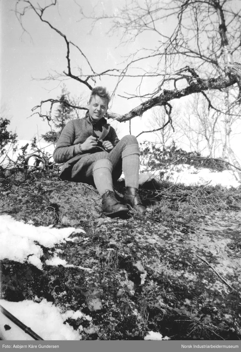 En gutt sitter ute i naturen. Delvis snø