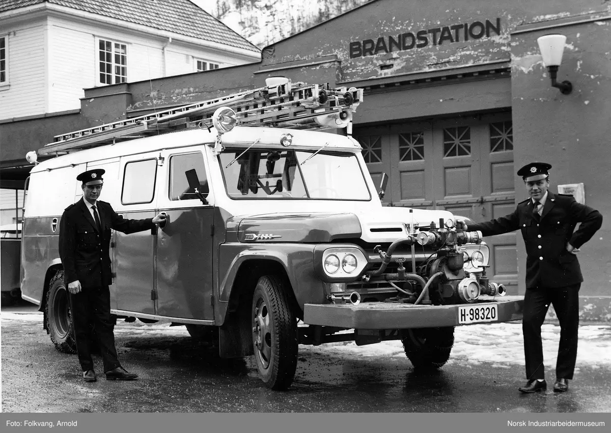To brannmenn stående ved brannbil tilhørende Tinn Kommune. Brannbil av typen Amerikansk Ford F500 1959 mod (Ford 292 V8 motor).