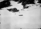 Flygfotografi av Hägernäs flygstation vintertid, 1923. Logementsfartyg i isen och tälthangarer vid strandkant.