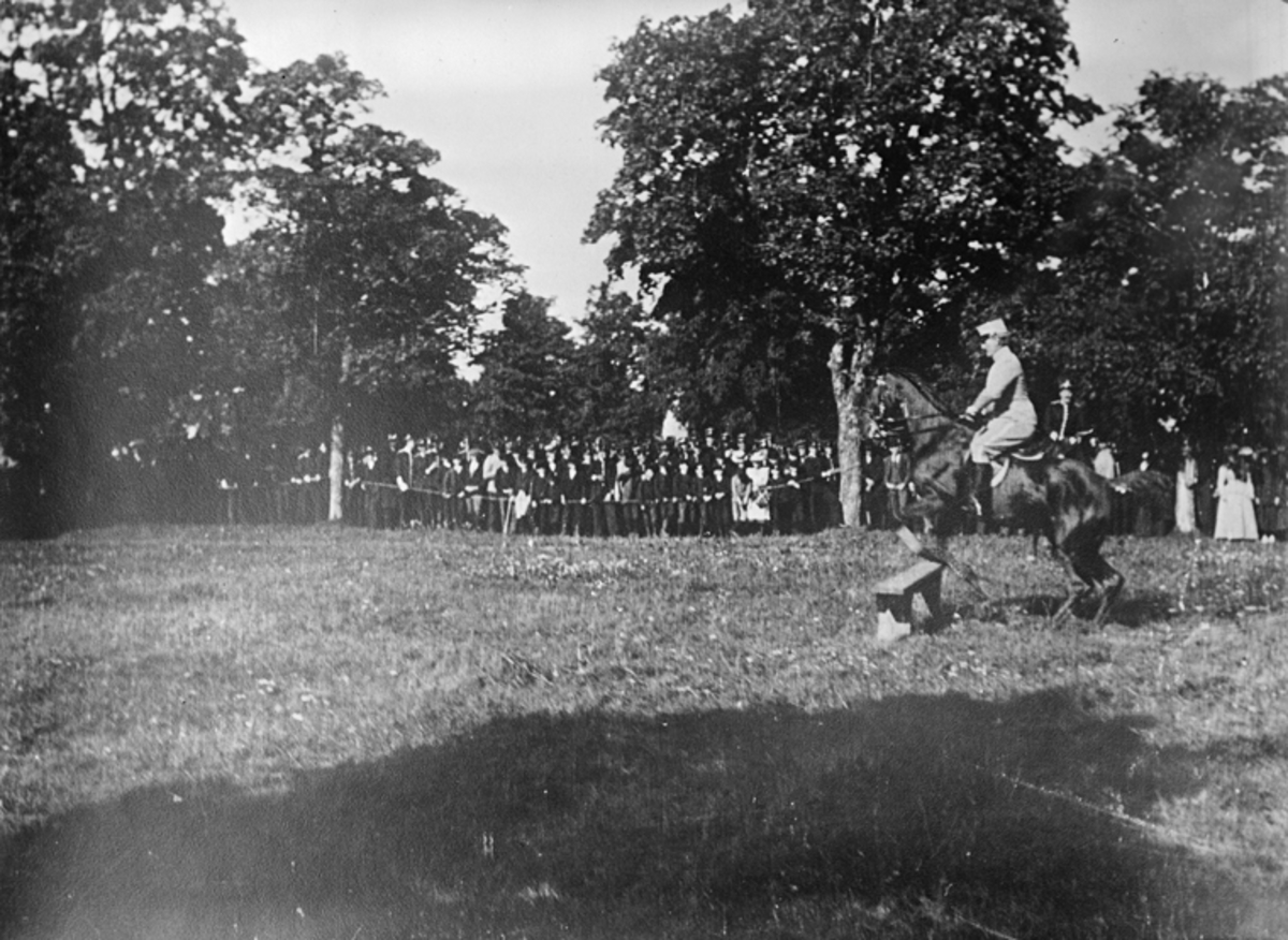 Militär utövar hästhoppning framför publik på regementsområdet Malmen.