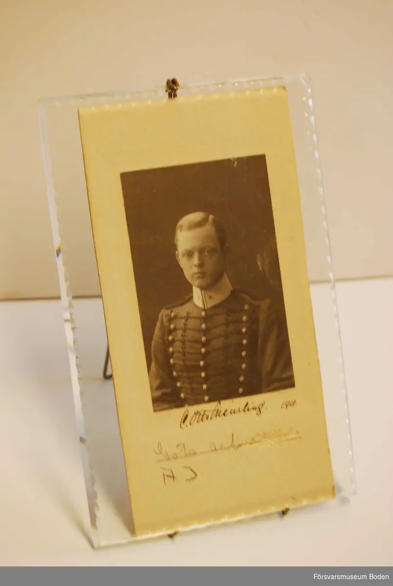 Porträtt av man i uniform, sannolikt Carl Otto Meurling vid A3, daterat 1911. Tjock glasskiva med avfasade kanter, avsett att ställas på bord. Utan ram, hålles ihop med trådkonstruktion som samtidigt fungerar som stöd.