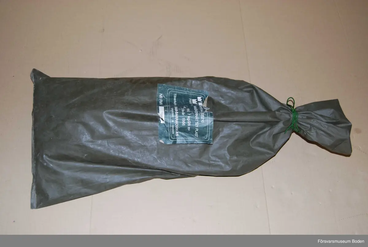 Maskeringsnät i säck av plastväv, materielnummer M1514-005210. Tillverkat 1986 av Diab-Barracuda, Gamleby. Nr 30194.