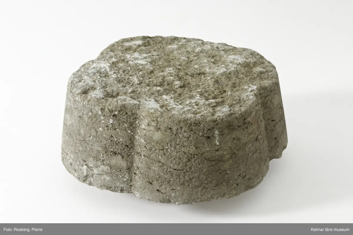 KLM 35218:2:1-2. Dopfuntsfot, av kalksten, 2 delar. Mått, hela foten: höjd 40 cm, största bredd 43 cm. Foten sammansatt av fyra halvkolonner, konade med fyrklöverformad vulst upptill. Saknar fotplatta. Foten som är det enda som återstår av funten är eroderad efter lång tid utomhus. Den har en liten skada vid skarven och en horisontell spricka.