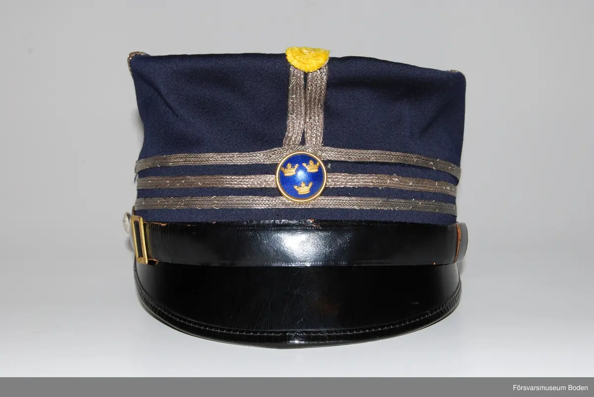Av mörkblått kläde med tre smala silvergaloner runt mössan betecknande kapten. Framtill gul kokard samt mössknapp i blå emalj för officerare. Mössremmen fastsatt med regementets knapp modell mindre.