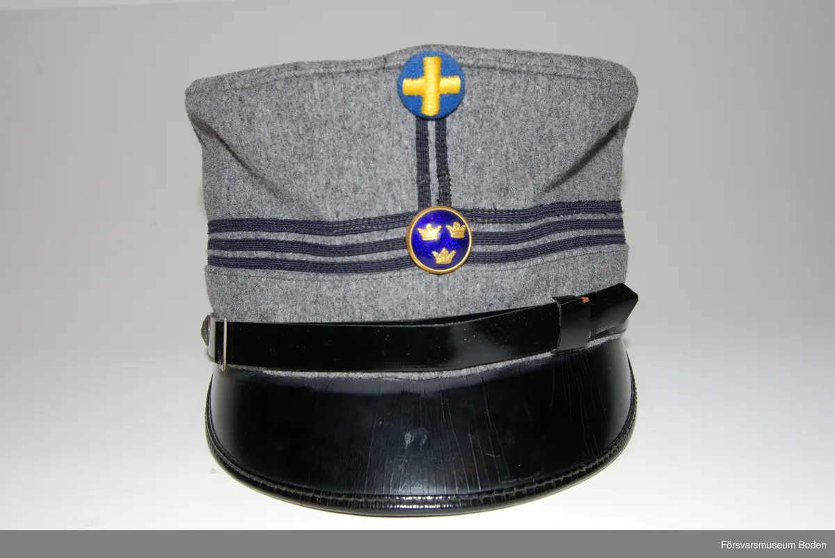 Ljusgrått kläde med tre smala band av blått kläde runt mössan betecknande kapten. Framtill mössmärke m/1865 i blå emalj samt upptill landstormsmärke m/1926 med gult broderat kors på blått kläde. Mössremmen fäst på sidorna med landstormens knapp modell mindre. Buren av fil. dr Arvid Moberg.