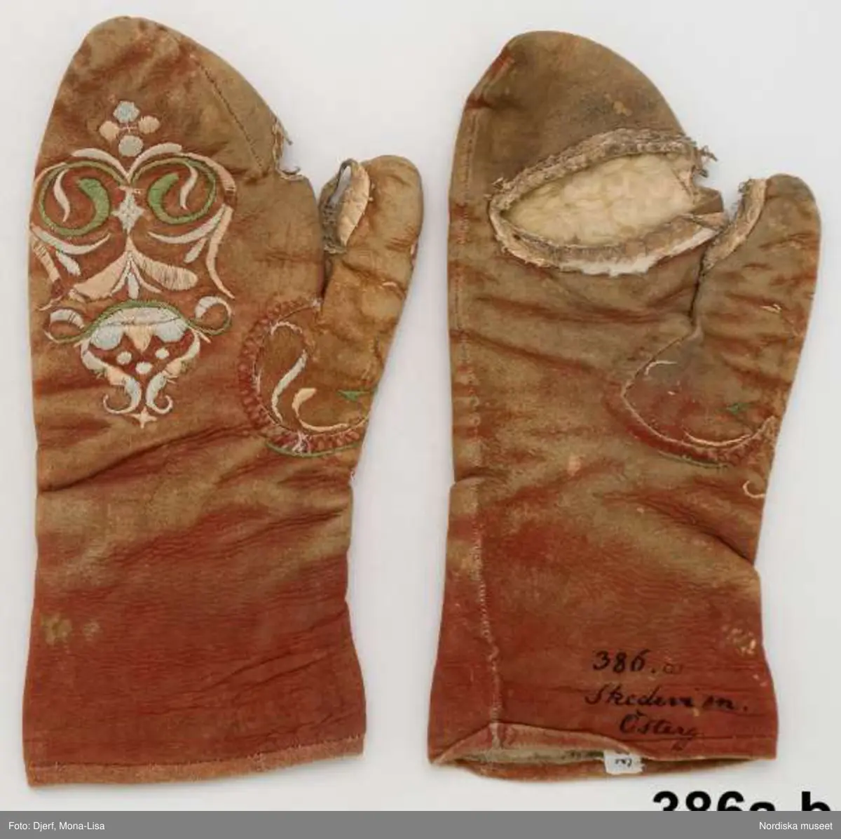 1 par tumhandskar  för kvinna av rödbrunt sämskat  fårskinn med  pälsfoder, spetsiga i framkant, slits på handens insida där fingrarna kan sticka ut. Broderi på handens ovansida, stiliserat  blommönster i plattsöm och flätsöm med silke i vitt, ljusblått , ljusrosa och ljusgrönt. Broderi även  kring tummens fäste. Bars vintertid till kyrkdräkten.
Anm. Handskarna slitna. 
 Sådana silkebroderade skinnhandskar i standardutförande  köptes i samband med bröllopet som gåva till bruden. 
/Berit Eldvik 2013-02-26