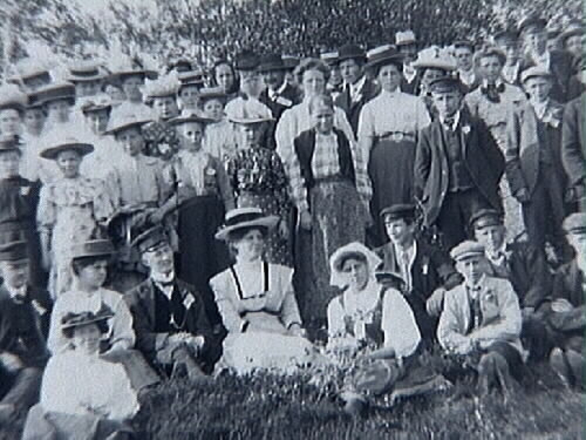 Gruppbild av ett otal kvinnor och män fotograferade utomhus. Samma motiv som neg.nr. B403.