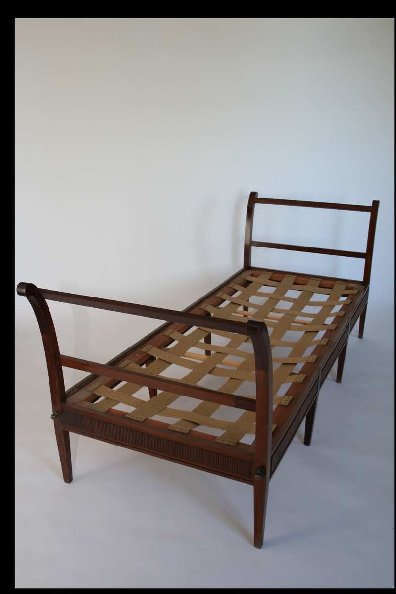 Empiresofa i mahogni. Rette spinkle bein, lett utsvingte vanger. Løs ryggpute og to løse pøller.