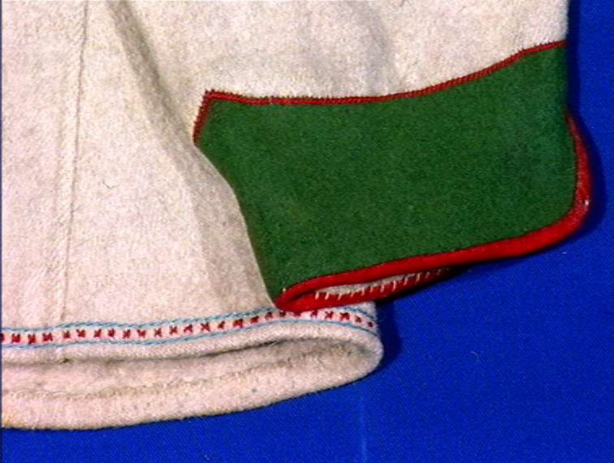 Hvit mannskofte av vadmal med gønne kanter av klede (oppslag).
Nedrekanter, ermebryninger og halskrage har dekor av rød korstign avgrenset av blått konturstign (ullgarn).
Halskrage ha kanting av svartklede med tittkant av rødt klede.
Ermer har et ca. 6,5 cm bredt belegg av grønn klede kantet med rødt klede.