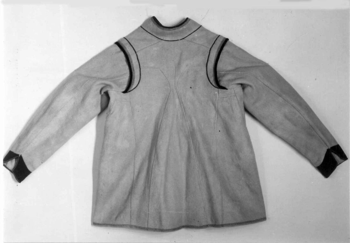 Hvit mannskofte av vadmal med gønne kanter av klede (oppslag).
Nedrekanter, ermebryninger og halskrage har dekor av rød korstign avgrenset av blått konturstign (ullgarn).
Halskrage ha kanting av svartklede med tittkant av rødt klede.
Ermer har et ca. 6,5 cm bredt belegg av grønn klede kantet med rødt klede.