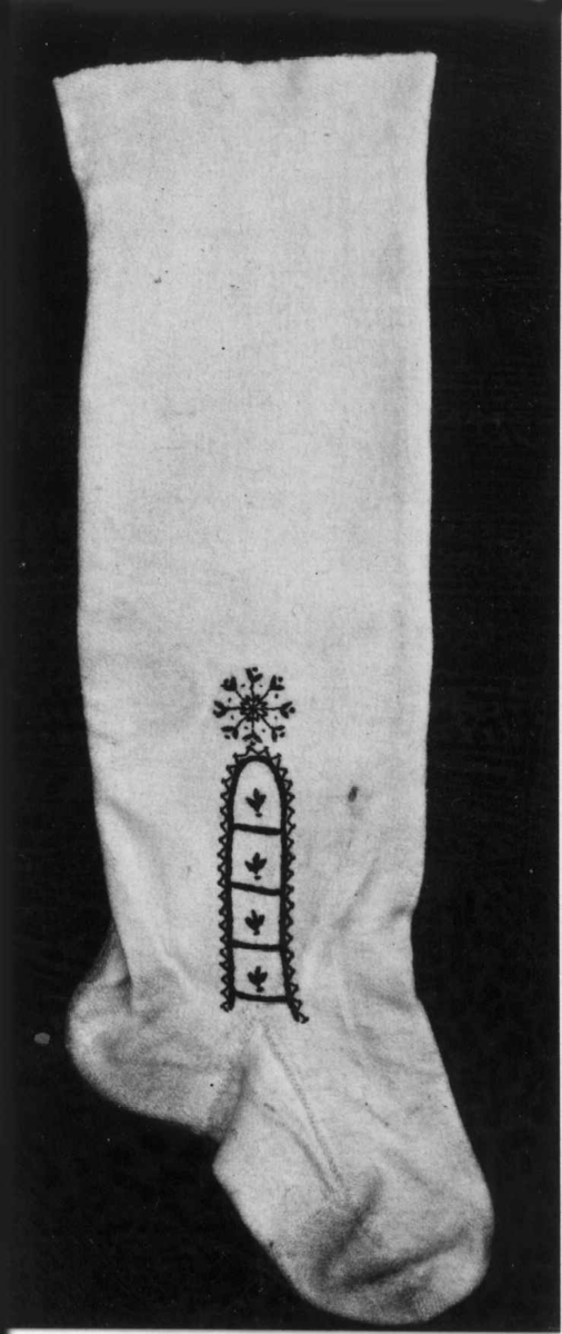 Hvite sydde strømper av vadmel med brodert dekor i svart.