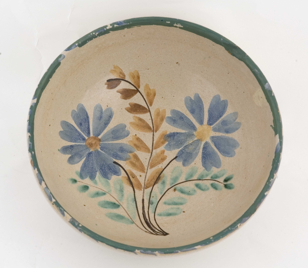 Beige keramikkbolle med flerfarget blomsterdekor i bunnen. 